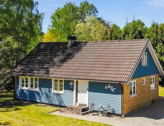 niebieski dom ze stołem i krzesłami przed nim w obiekcie Moonstone Meadow w mieście Ludvigsborg