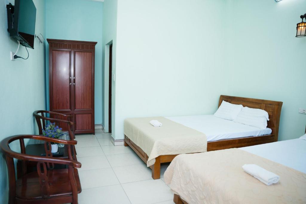 a hotel room with two beds and a chair at Khách Sạn Mai Hà Sầm Sơn in Sầm Sơn