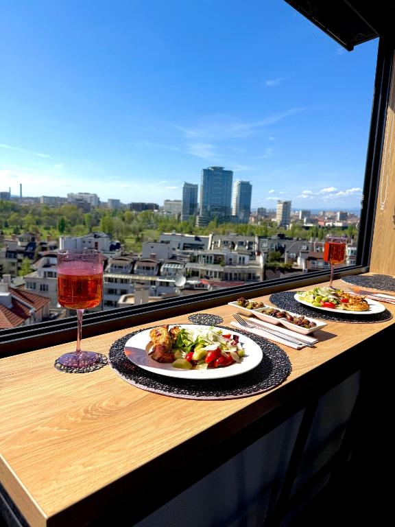 two plates of food on a table with wine glasses at Blue Iris, 2BR, Stunning Views, Jacuzzi and Workspace in Sofia