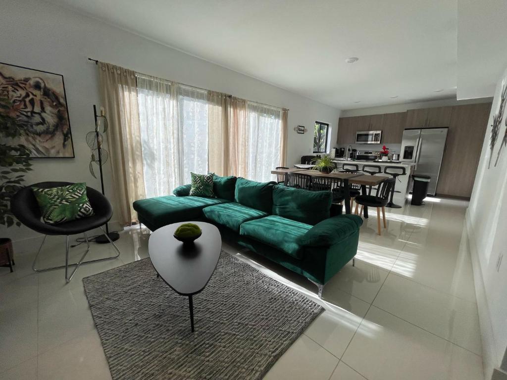 Una sala de estar con un sofá verde y una mesa. en ! Espectacular casa del bosque !, en Florida City