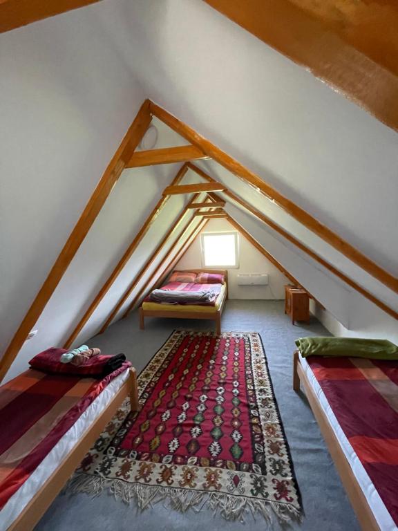 a attic room with two beds and a rug at NINO Natural wood house in Visoko