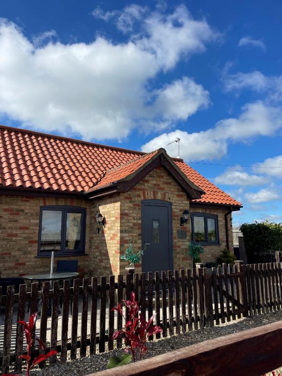 a small brick house with a wooden fence at Oxley Cottage in Alford