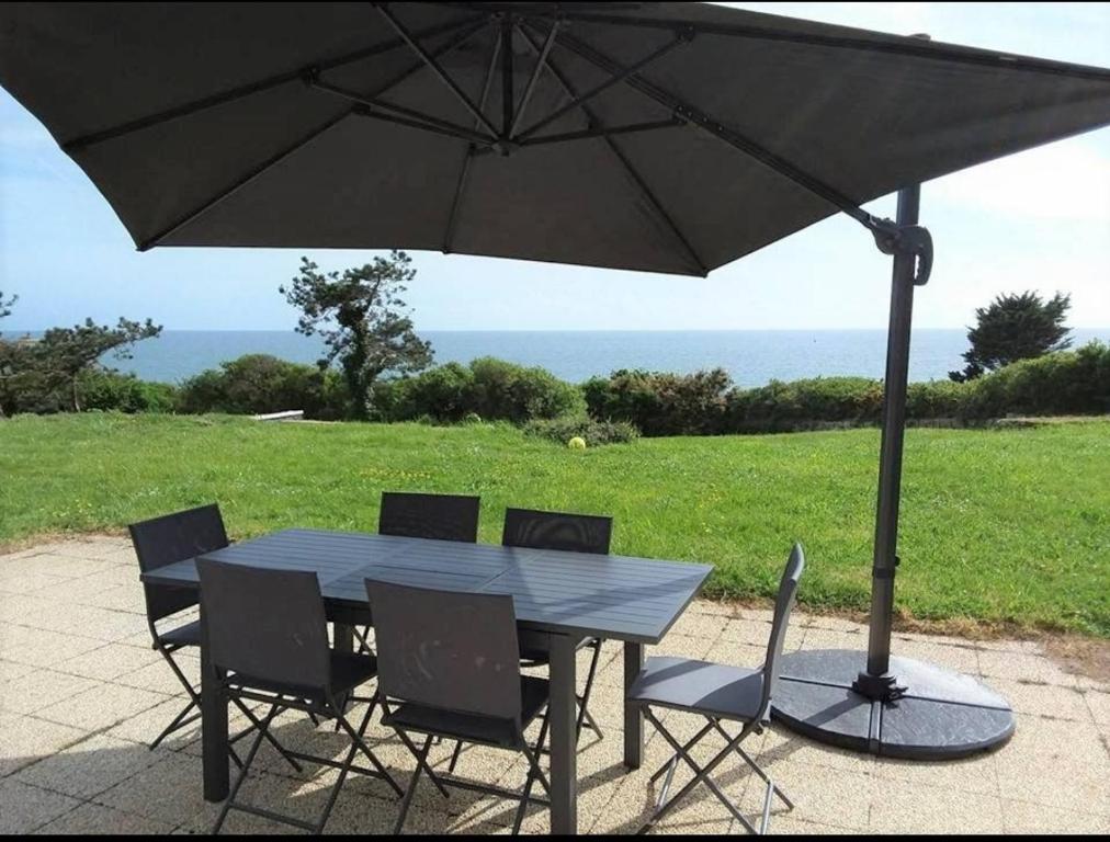 - une table et des chaises sous un parasol sur la terrasse dans l'établissement Maison vue mer 8 personnes - Finistère Sud, à Moëlan-sur-Mer
