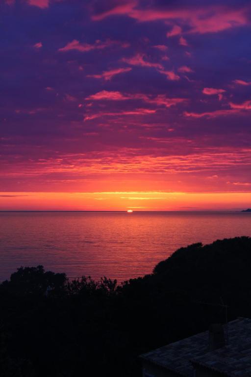 - un coucher de soleil sur l'océan au loin dans l'établissement Appartement proche des plages de sable, à Grosseto-Prugna