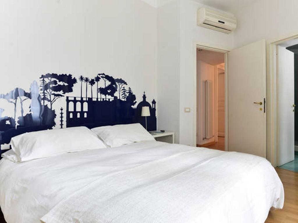 um quarto com uma cama branca e um mural na parede em Viadelloca35 em Roma