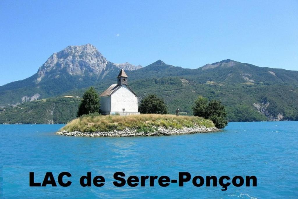 une petite île avec une église au milieu d'un lac dans l'établissement La Cévane, à Chorges