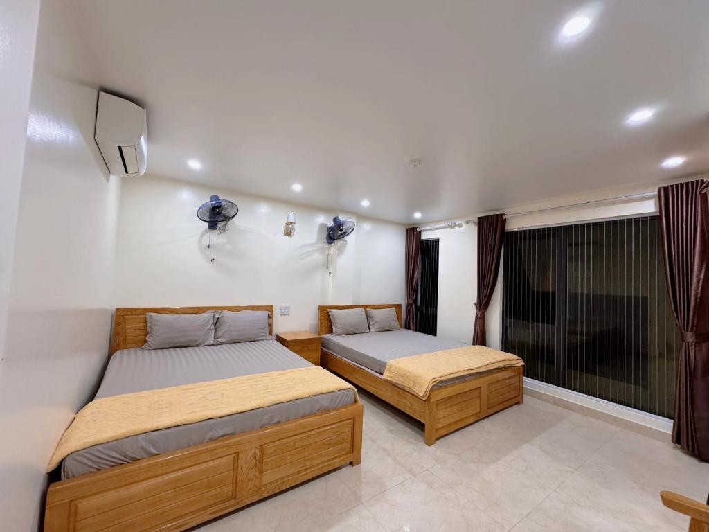 Un dormitorio con dos camas y un televisor en la pared. en Minh Đức hotel, en Cat Ba