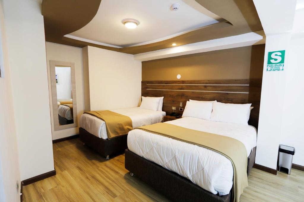 una camera d'albergo con due letti e uno specchio di INKALAM cusco a Cuzco