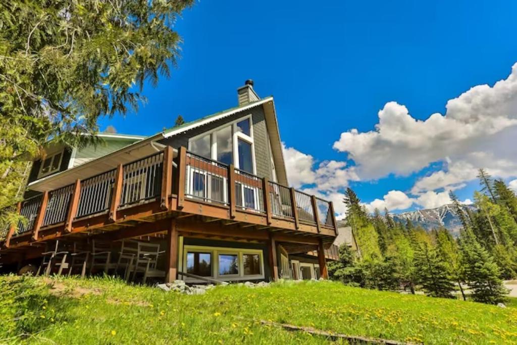 a house on a hill with mountains in the background at Dog friendly Home on Ski Hill with Hot Tub by StayIn in Fernie