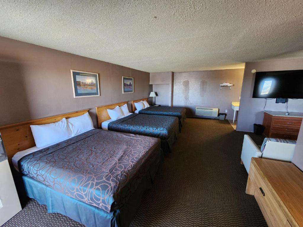a hotel room with two beds and a flat screen tv at Satellite Inn in Alamogordo