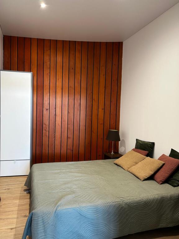 - une chambre avec un lit et un mur en bois dans l'établissement Montciel Jura, à Lons-le-Saunier