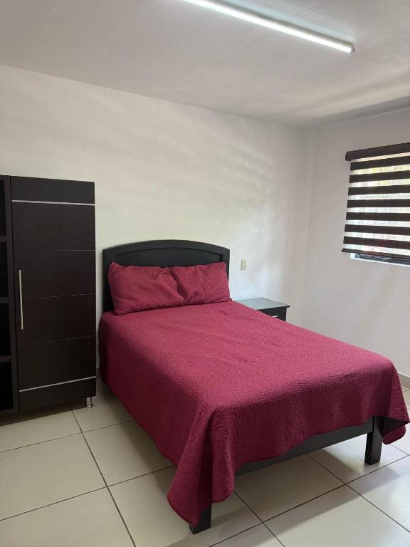 ein Schlafzimmer mit einem Bett mit einer rosa Decke in der Unterkunft Hotel "El origen de BRICM" in Tequila