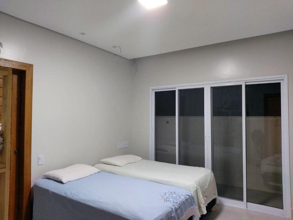 two beds in a room with white walls at Quarto Carillo in Porto Seguro