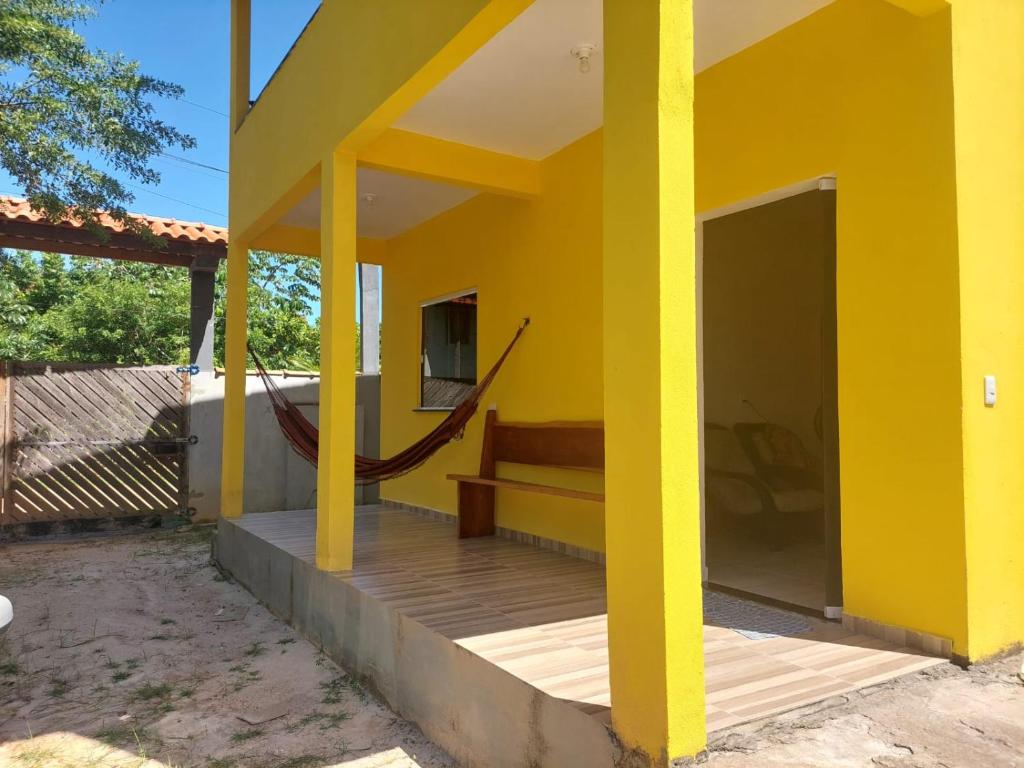 a yellow house with a wooden floor and a porch at Aconchego da Zuca in Marau