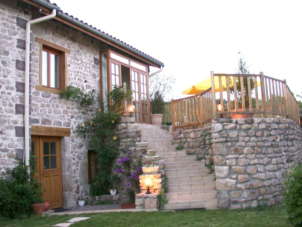 une maison en pierre avec des escaliers et un mur en pierre dans l'établissement Au Bout du Monde, à Chaspinhac
