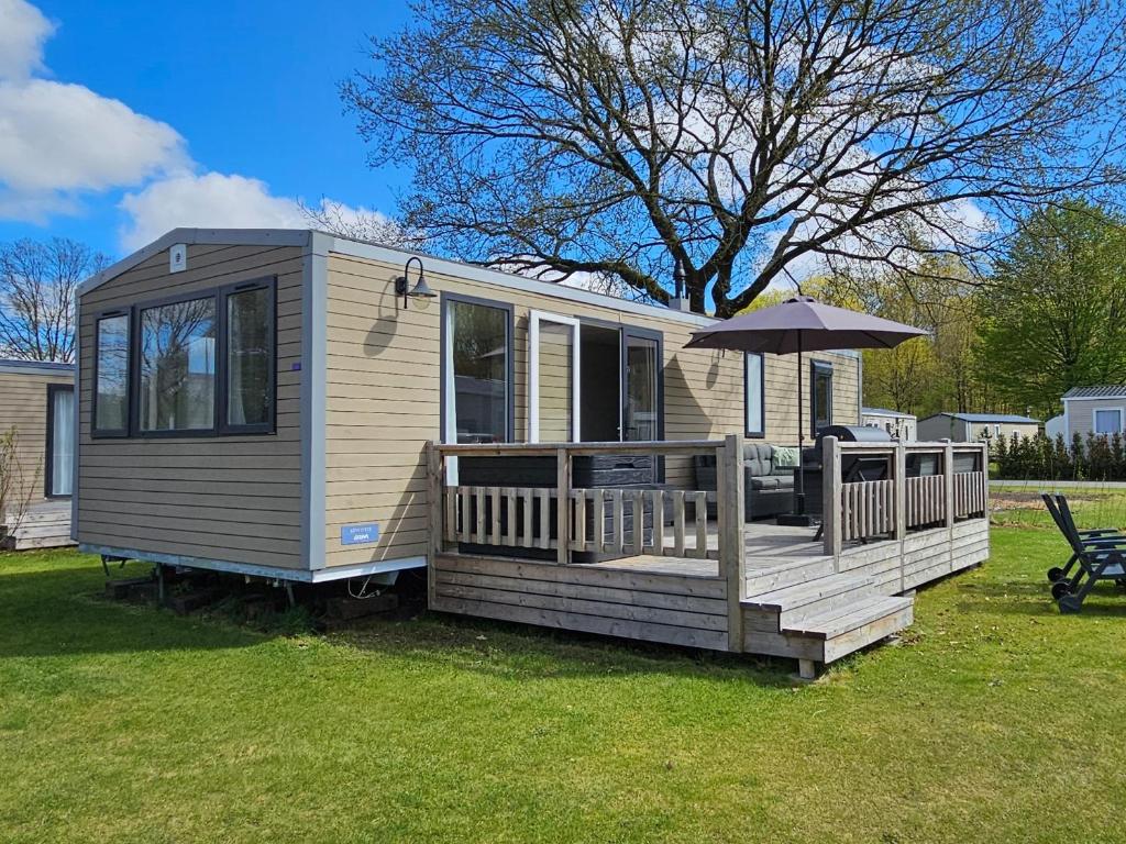 a tiny house with a deck with an umbrella at Chalet Zomerdroom Gasselte in Gasselte