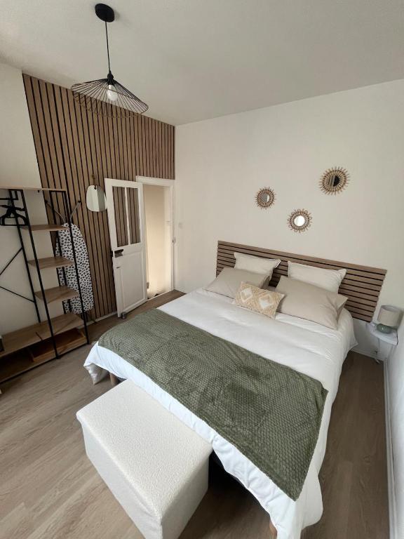 - une chambre avec un grand lit blanc et un banc dans l'établissement La P'tite Maison D'Auron, à Bourges