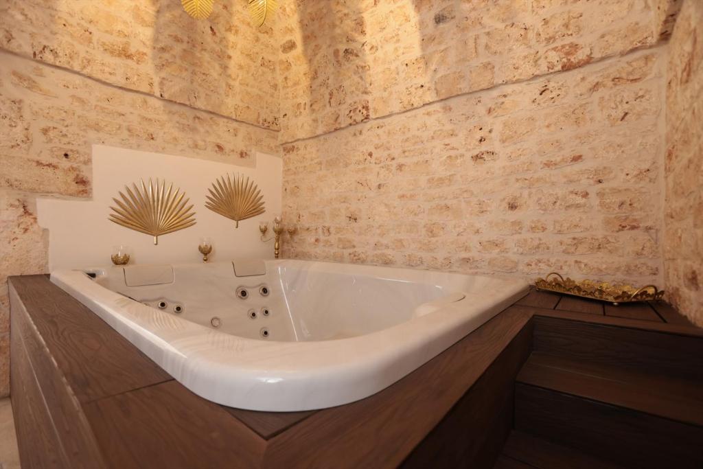 a white bath tub in a bathroom with brick walls at Ántika suite & spa in Castellana Grotte