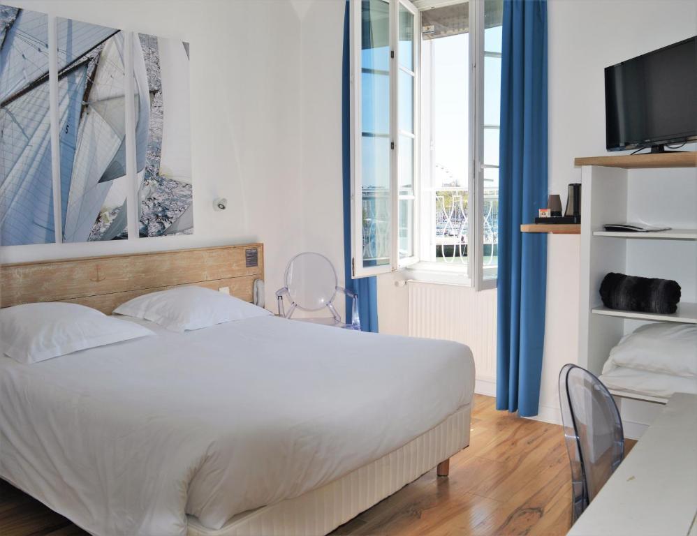 - une chambre avec un lit, un bureau et une télévision dans l&#39;établissement Hotel La Marine, Vieux Port, à La Rochelle