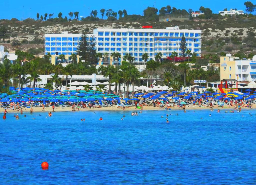 a group of people on a beach with blue umbrellas at Corfu Hotel in Ayia Napa