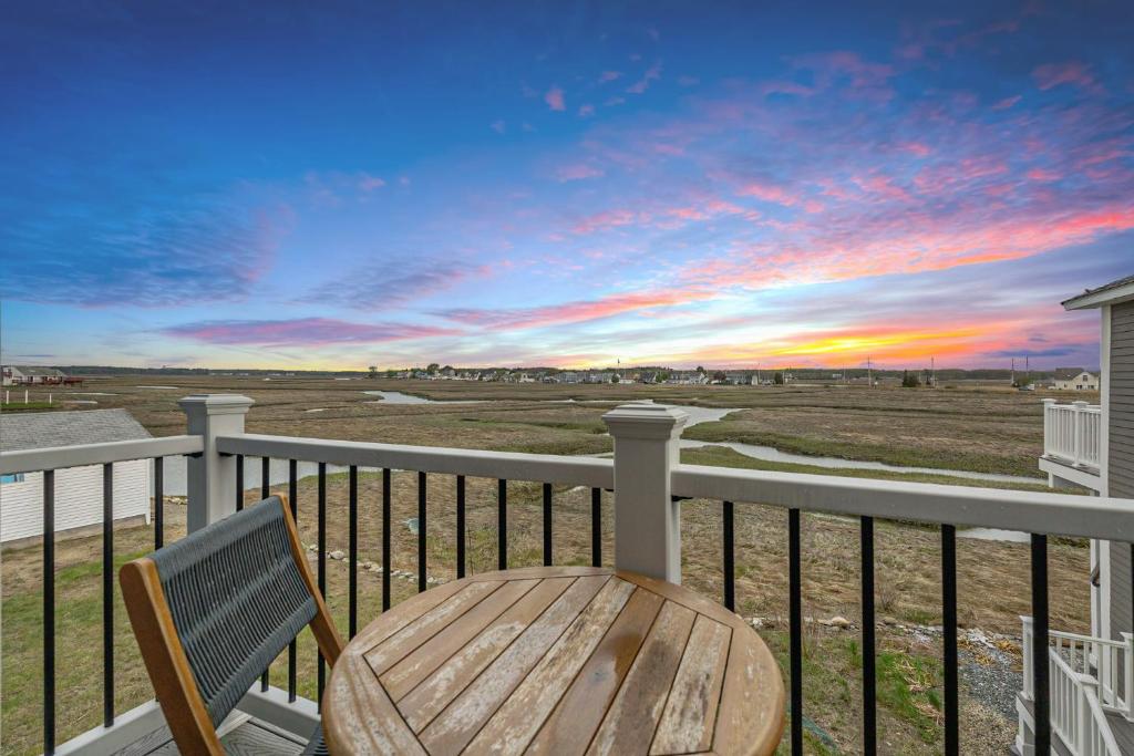 a wooden table and chair on a balcony with a sunset at Sunset Views Balcony Marsh Views AC in Hampton
