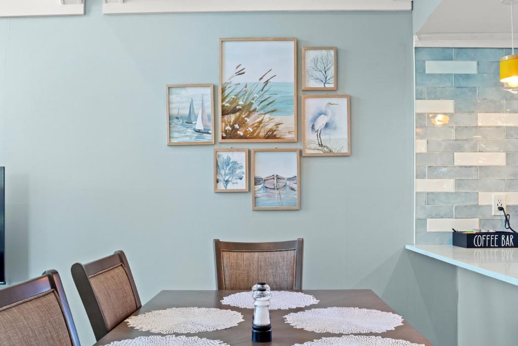 ein Esszimmer mit einem Tisch und sechs Bildern an der Wand in der Unterkunft Ocean&#39;s Bliss at Arcadian Dunes in Myrtle Beach