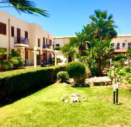 a yard with palm trees and a building at La perla marina casa vacanza in San Vito lo Capo