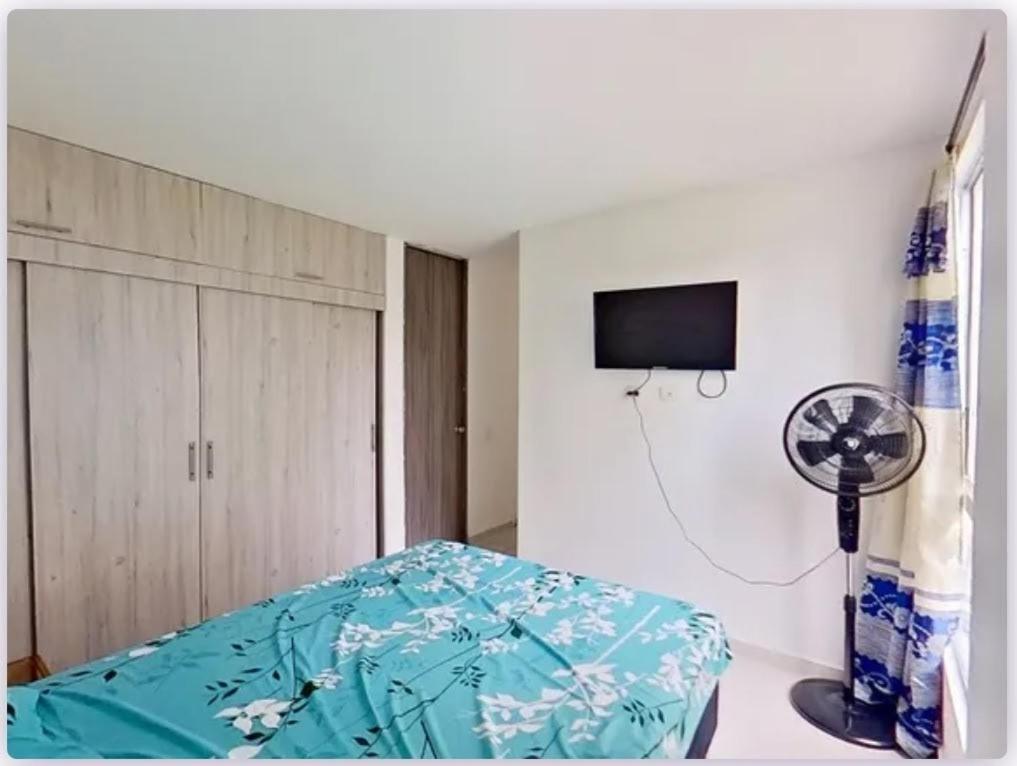 Serenity Inn Jamundi في Jamundí: غرفة نوم بسرير ومروحة وتلفزيون