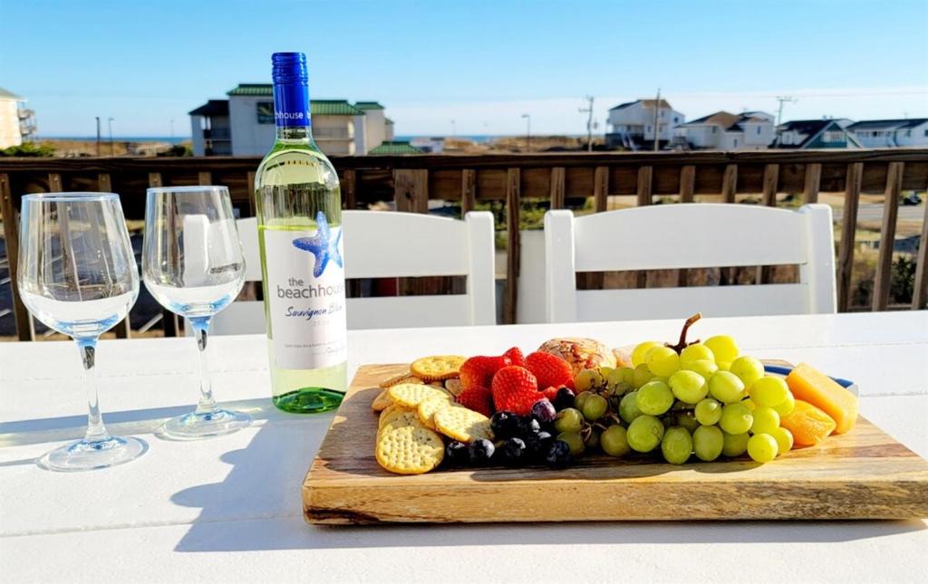 a plate of fruit on a table with a bottle of wine at Monumental Waves in Kill Devil Hills