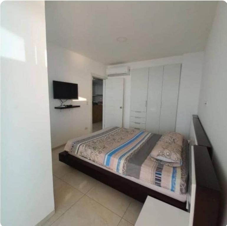 ein Schlafzimmer mit einem Bett und einem Fernseher in der Unterkunft Tonsupa, Suite Grand Diamond Beach in Tonsupa