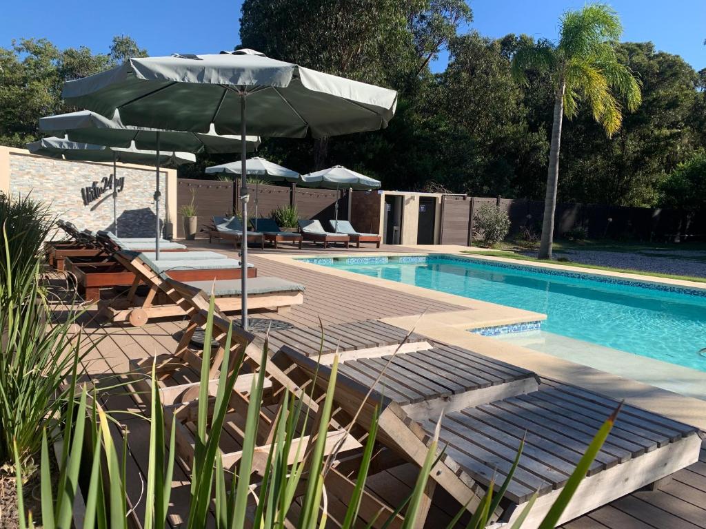 a swimming pool with chairs and umbrellas next to a swimming pool at Vista24uy Ref1001 in Bella Vista