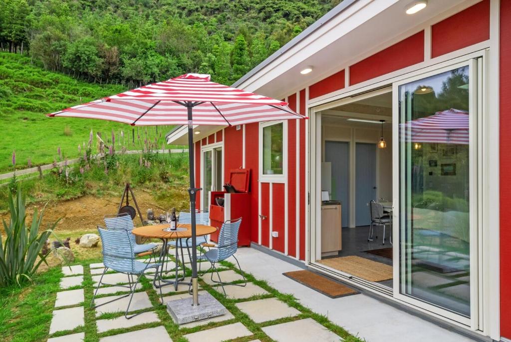 Reikorangi2 Bedroom Eco Cottage - Waikanae的带桌椅和遮阳伞的露台