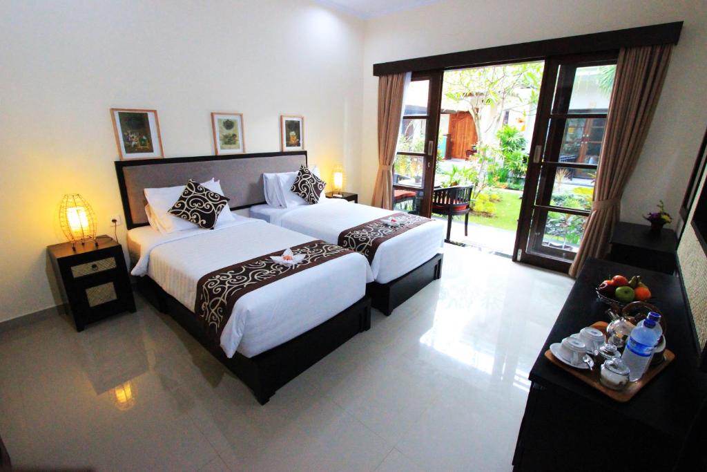 a hotel room with two beds and a balcony at Gatra Ubud Inn in Ubud
