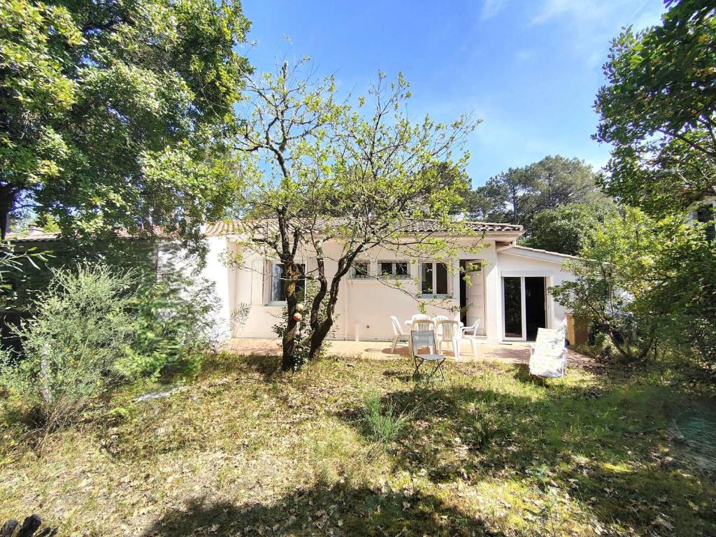 une maison blanche avec un arbre dans la cour dans l'établissement Villa calme entre bassin et océan, terrasse, 4 pers. - FR-1-736-60, à Lège-Cap-Ferret