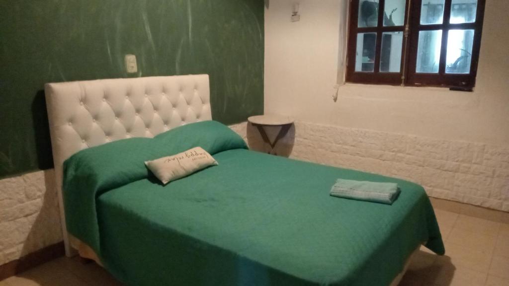 Cama verde en habitación con ventana en Sol y Luna, en Termas de Río Hondo