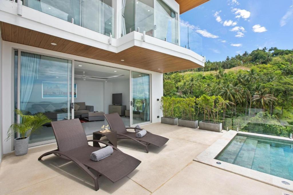 an indoor patio with chairs and a swimming pool at Villa The Wave in Chaweng Noi Beach