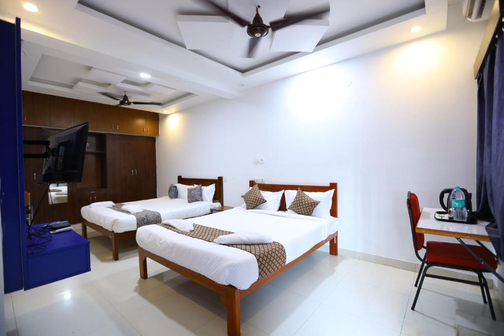 a bedroom with two beds and a tv and a desk at Hotel Starlight Chennai near DLF,L&T,Miot,Tradecenter,Ramachandra medical coll in Chennai