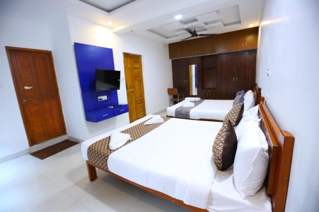 a bedroom with two beds and a flat screen tv at Hotel Starlight Chennai near DLF,L&T,Miot,Tradecenter,Ramachandra medical coll in Chennai