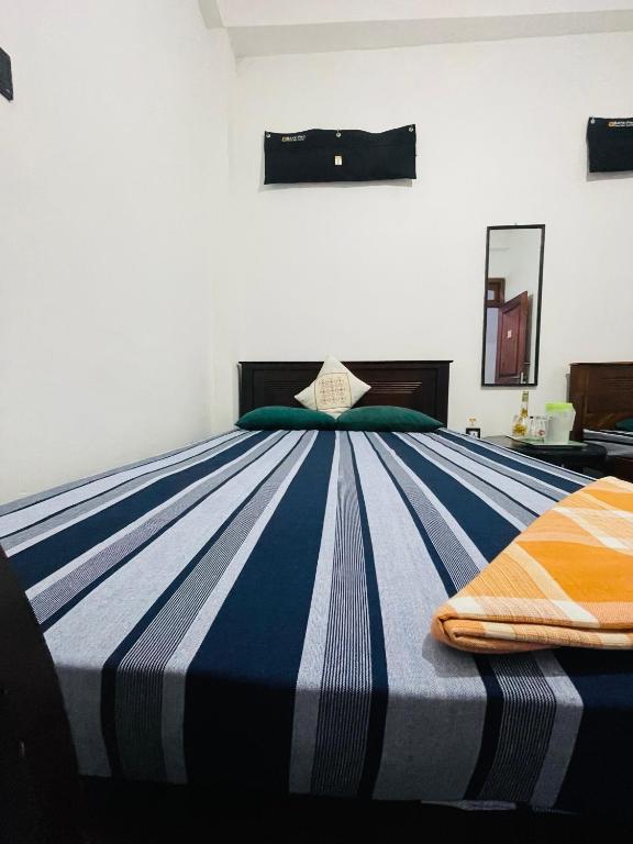 a bedroom with a blue and white striped bed at Suriya Haven Homestay in Badulla