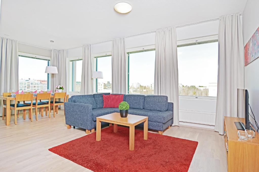 a living room with a blue couch and a table at Forenom Serviced Apartments Tampere Pyynikki in Tampere