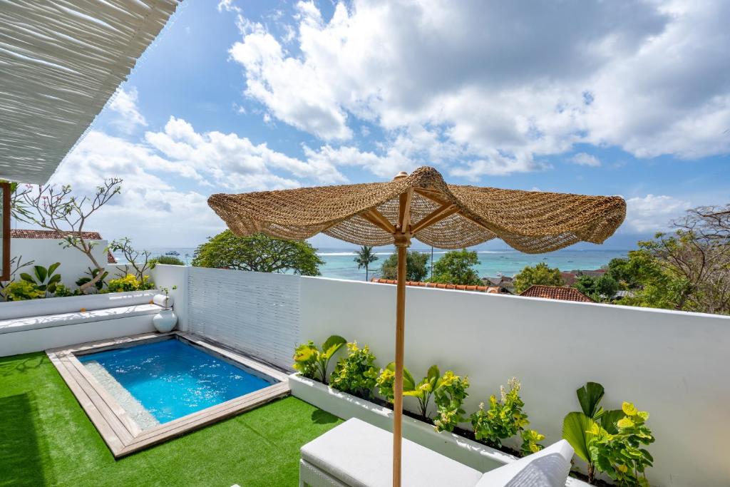 a patio with an umbrella and a swimming pool at Beach Tonic Lembongan in Nusa Lembongan