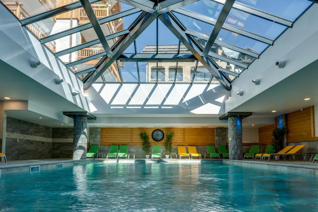 a swimming pool in a building with a skylight at CGH Résidences & Spas Le Napoléon in Montgenèvre