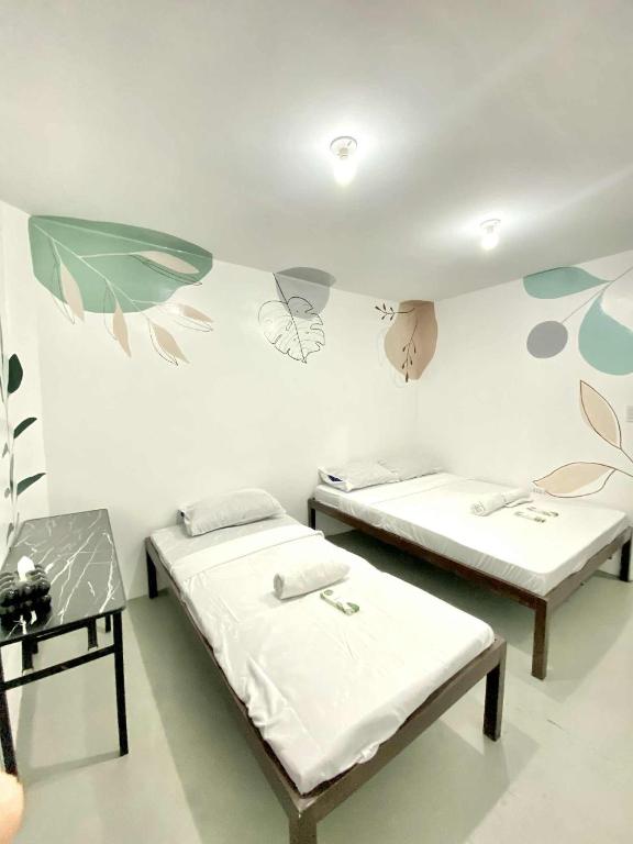 two beds in a room with flowers painted on the wall at Inn Convenience in Coron
