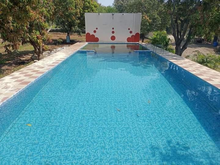 a large blue swimming pool with a sign in the background at Van Vagdo Prakruti Nivas in Sāsan Gīr
