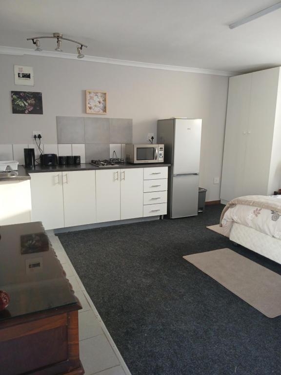 una cocina con armarios blancos y una cama en una habitación en Cozy, self-catering Garden Flat, en Ciudad del Cabo