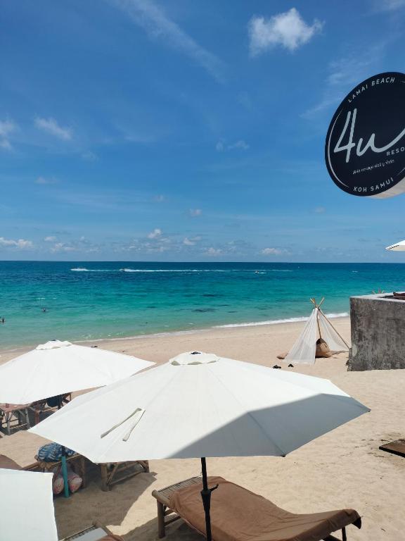 two umbrellas and chairs on a beach with the ocean at 4U Resort Samui in Lamai