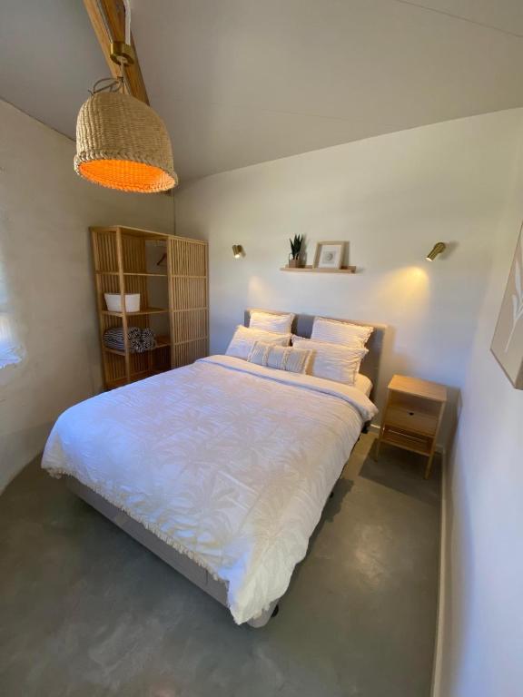 a bedroom with a large bed with white sheets and pillows at Whales and Bales in Bremer Bay