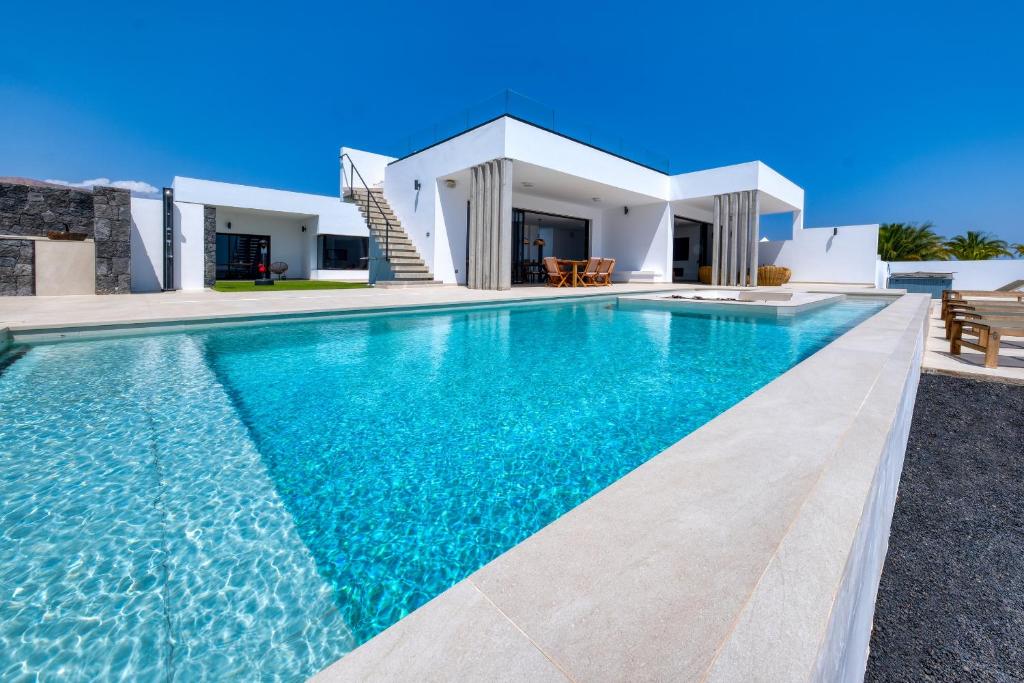 a swimming pool in front of a villa at White House - Fire pit and Private pool By Lanzarote Vacation Homes in Puerto Calero