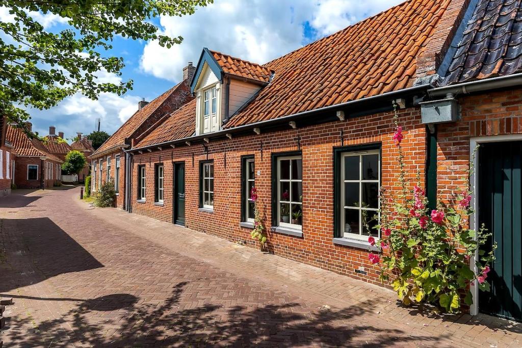 Un edificio de ladrillo con techo rojo en una calle. en Winsum - Groningen - 6 pers. Cosy Cottage - Op en Bie t Woater, en Winsum