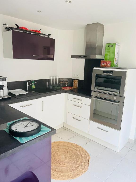 une cuisine avec des armoires blanches et un four dans l'établissement Petite maison agréable climatisée, à Nègrepelisse